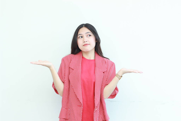 retrato de bela mulher asiática vestindo roupa vermelha com gesto confuso isolado no fundo branco. - Foto, Imagem