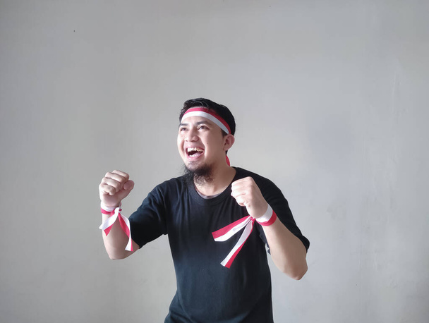 Молодий азіатський чоловік з щасливим успішним виразом і одягнений у чорний верх, прапор. Концепція Дня незалежності Індонезії. - Фото, зображення