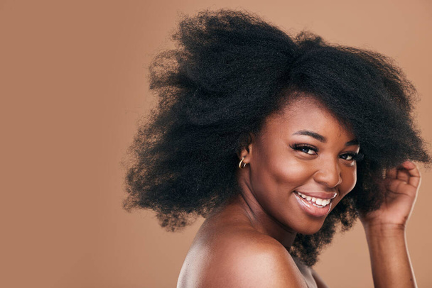 Portrait, hair care and black woman with smile, beauty and wellness on a brown studio background. Mockup space, person and model with texture, afro and natural with aesthetic, makeup and cosmetics. - Foto, Imagem