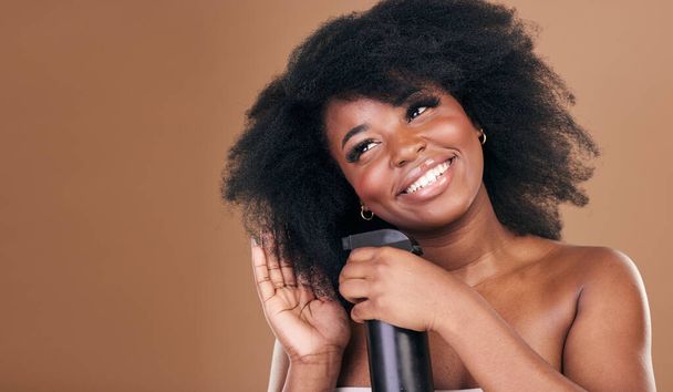 Denken, Haare und Spray mit einer schwarzen Model-Frau im Studio auf braunem Hintergrund für Naturkosmetik. Gesicht, Lächeln und Haarpflege mit einer glücklichen Afro-Frau drinnen zur Trockenshampoo-Behandlung. - Foto, Bild