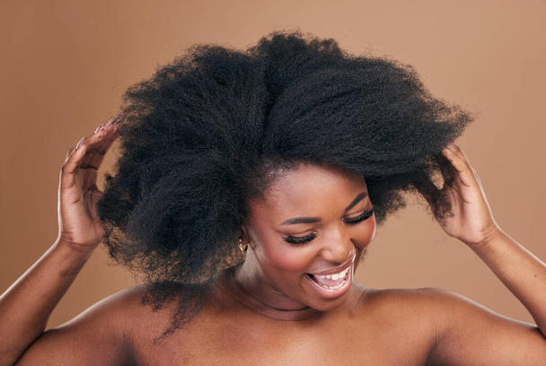 Beauty, hair and crazy with a model black woman in studio on a brown background for natural cosmetics. Face, smile and haircare with a playful young afro female person indoor for shampoo treatment. - Φωτογραφία, εικόνα