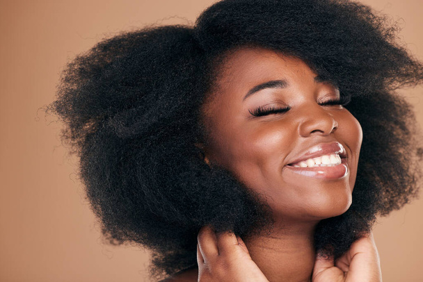 Natural beauty, black woman and care for afro hair, smile and volume on a brown studio background. Aesthetic, hairstyle and African model with cosmetics after salon treatment, wellness and texture. - Photo, Image