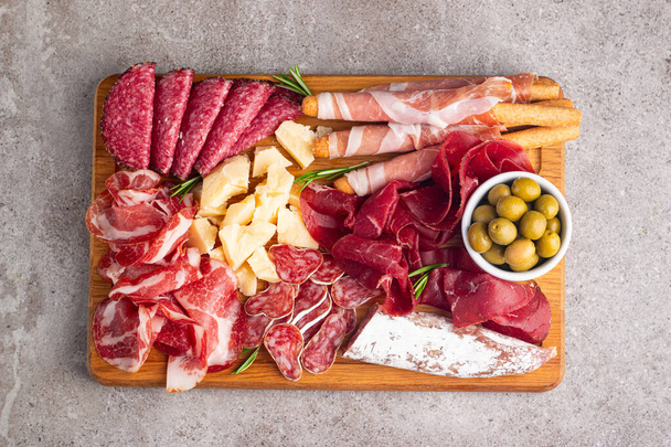 Charcuterie board. Antipasti appetizers of meat and cheese platter with salami, prosciutto crudo or jamon and olives - Photo, Image