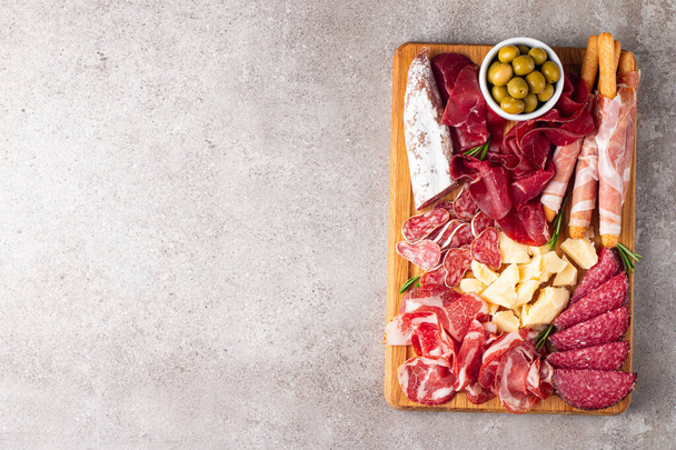 Charcuterie board. Antipasti appetizers of meat and cheese platter with salami, prosciutto crudo or jamon and olives - Photo, Image