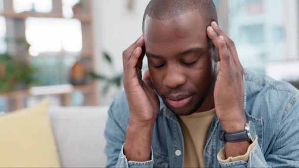 Anxiety, headache and black man on sofa with temple massage for brain fog in his home. Stress, migraine and African male frustrated by vertigo, pain and mental health, worry or crisis in living room. - Footage, Video