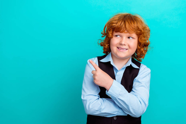 Photo portrait of charming curly redhead boy look point empty space wear trendy school garment isolated on aquamarine color background. - Photo, Image