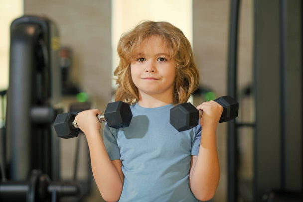 Sport activities at leisure with children. Blonde boy holding dumbbells. Sports exercises for children. Funny child lifting the dumbbells - Photo, Image