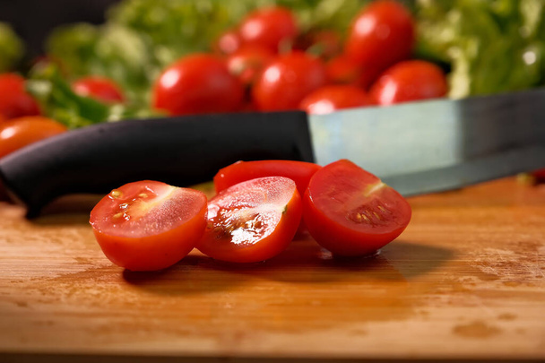 czerwone pomidory na gałęzi. krople wody. zbliżenie. Liście sałaty. nóż - Zdjęcie, obraz