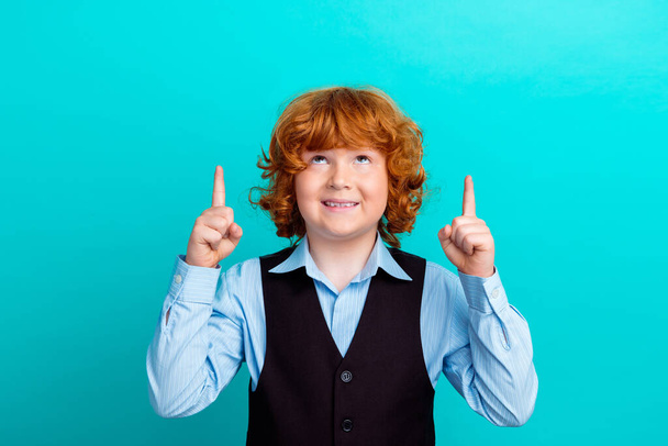 Photo portrait of adorable foxy wavy hair boy look up empty space wear trendy school uniform outfit isolated on aquamarine color background. - Photo, Image