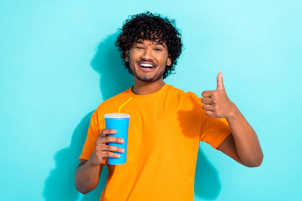 Photo of handsome guy toothy smile hold soda drink straw cup demonstrate thumb up isolated on teal color background. - Fotografie, Obrázek