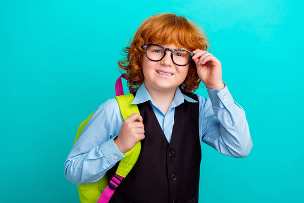 Photo of little cute schoolkid arm touch eyeglasses carry backpack toothy smile isolated on teal color background. - Foto, Imagem