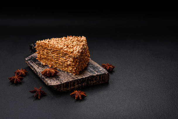 Delicious sweet puff waffle cake with cream and nuts cut into pieces on a textured concrete background - Photo, Image