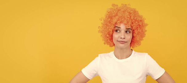 astuzia ragazza divertente con look fantasia indossa parrucca capelli arancioni su sfondo giallo, emozioni. Donna ritratto volto isolato, banner con spazio copia - Foto, immagini