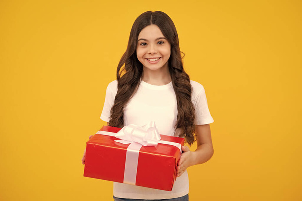 Child with gift present box on isolated background. Presents for birthday, Valentines day, New Year or Christmas. Happy teenager, positive and smiling emotions of teen girl - Photo, image