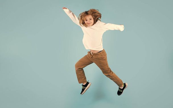 Hauska poika hyppää. Täyspitkä kuva lapsi poika hypätä korkea kulumista rento ruudullinen paita eristetty keltaisella pohjalla. Hyppäävän pojan muotokuva. Lasten hyppääminen, hauskanpito - Valokuva, kuva