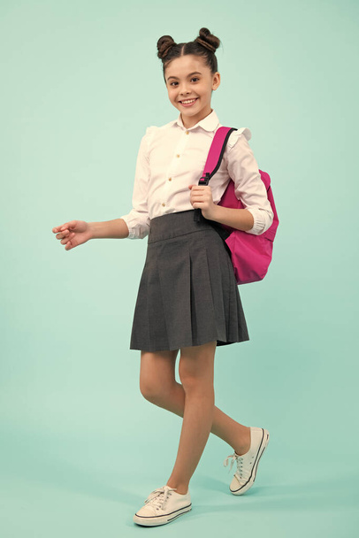 Zurück zur Schule. Teenager-Schulmädchen in Schuluniform mit Rucksack. Schulkinder auf isoliertem, blauem Hintergrund - Foto, Bild