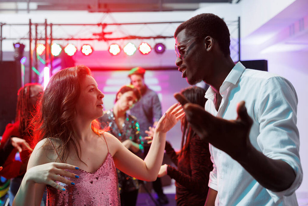 Mies ja nainen erilaisia ystäviä tanssia yhdessä ja chattailuun yökerho disco puolue. Nuori monirotuinen pari klubi ja hauskaa tanssilattialla diskossa klubilla - Valokuva, kuva