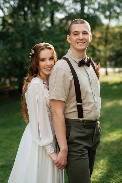 wedding walk of the bride and groom in a coniferous park in summer - Photo, Image