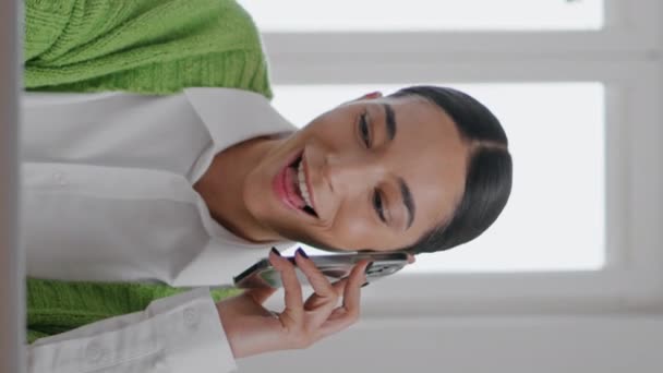 Θετική freelancer συνομιλία κινητό στο δωμάτιο κάθετη shot closeup. Ευτυχισμένο χαρούμενο μαθητικό κορίτσι που μιλάει στο κινητό του χρησιμοποιώντας φορητό υπολογιστή μέσα. Χαμογελώντας νεαρή γυναίκα κουτσομπολεύει smartphone εργασίας υπολογιστή - Πλάνα, βίντεο