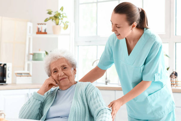 Vanhempi nainen naispuolisen hoitajan kanssa keittiössä - Valokuva, kuva