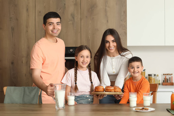 Glückliche Familie trinkt Milch mit Brötchen in der Küche - Foto, Bild