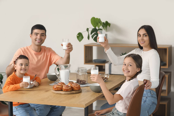 Счастливая семья пьет молоко на завтрак на кухне - Фото, изображение