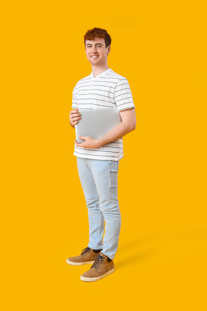 Programador masculino con portátil sobre fondo amarillo - Foto, imagen