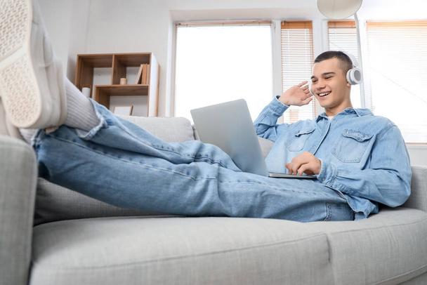 Молодой человек в наушниках с ноутбуком видео чата дома - Фото, изображение