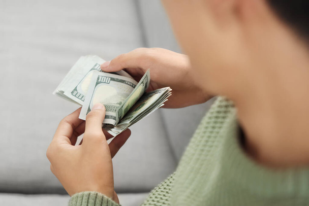 Fiatal férfi dollárbankjegyekkel otthon, közelkép - Fotó, kép