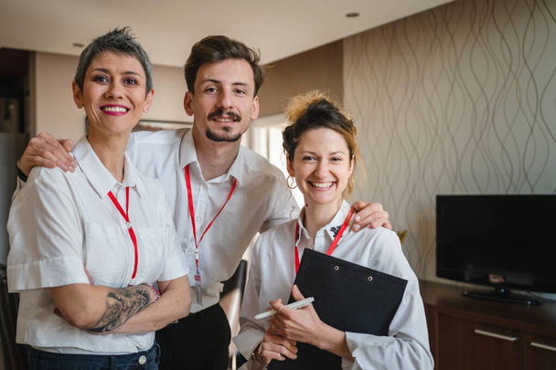 Портрет групи людей, що готуються до бізнес-конференції чоловік і жінки три людини стоять щасливою посмішкою в готельному номері, позуючи на камеру щасливою посмішкою, одягають білі сорочки реальні люди копіюють простір
 - Фото, зображення