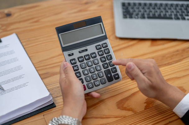 Close-up top view image of a professional businessman using a calculator at his desk. income, budget, financial, tax, sales - Photo, Image