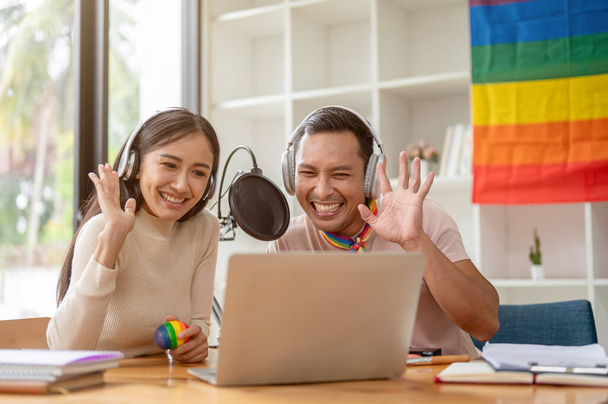 An attractive and happy Asian gay man enjoys reading comments online, talking, and streaming live podcasts online with his female colleague in the studio. - Foto, immagini