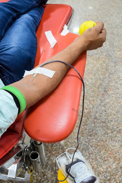 Blood donor at Blood donation camp held with a bouncy ball holding in hand at Balaji Temple, Vivek Vihar, Delhi, India, Image for World blood donor day on June 14 every year, Blood Donation Camp - 写真・画像