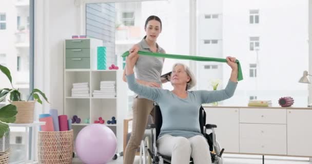 Rokkantsági, fizikoterápiás és nyújtózsinórral rendelkező idős nő testmozgás rehabilitációra, egészségügyi vizsgálatra vagy kiropraktikai szolgáltatásokra. Fizioterápia, tolószékben ülő betegek támogatása vagy segítése. - Felvétel, videó