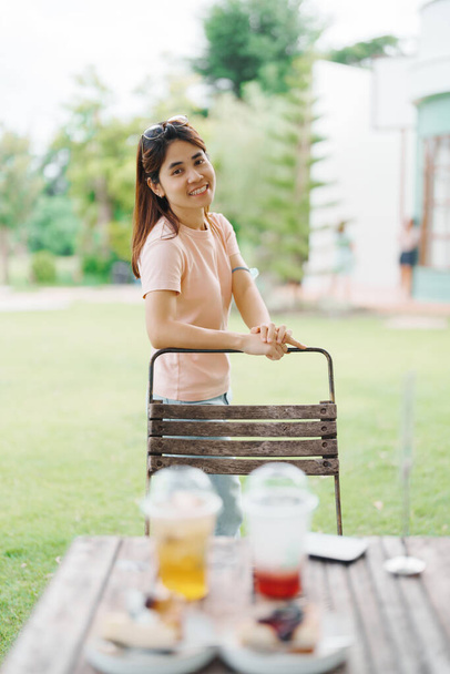 Ευτυχισμένη γυναίκα με επιδόρπιο στο καφέ, νεαρή Ασιάτισσα χαμογελώντας κατά τη διάρκεια του φαγητού κέικ και πίνοντας παγωμένο ποτό στο σπίτι - Φωτογραφία, εικόνα