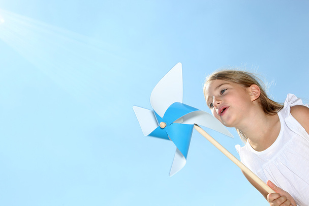 Little girl blowing blue wind wheel - Foto, Imagem