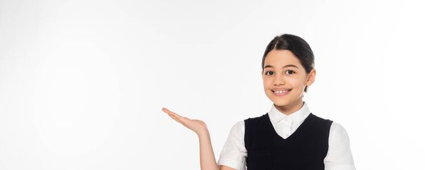 joyful schoolgirl showing something with hand, pointing and looking at camera, presenting, banner - Photo, Image