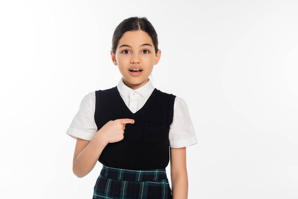 surprised schoolgirl pointing with finger at herself and looking at camera isolated on white, girl - Photo, Image