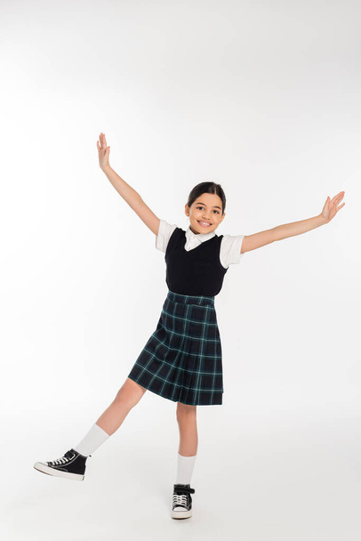 excited schoolgirl standing with outstretched hands isolated on white, full length, happiness - Фото, зображення