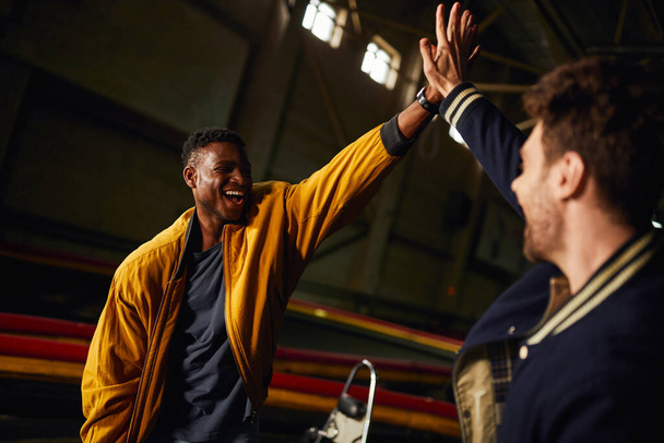 aufgeregt afrikanisch-amerikanischer Mann gibt High Five an Freund im Inneren der Kartbahn, Wettbewerb - Foto, Bild