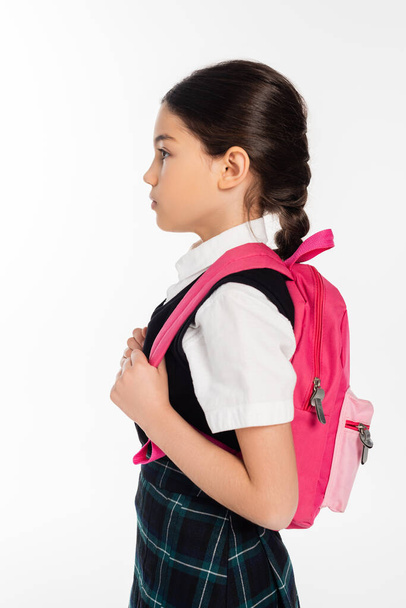 widok z boku, nastolatka uczennica stojąca z różowym plecakiem odizolowany na białym, powrót do koncepcji szkoły - Zdjęcie, obraz