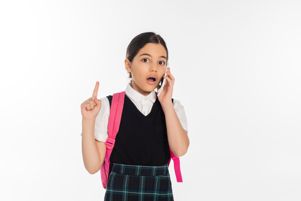 digitális kor, meghökkent iskolás lány hátizsák beszél okostelefon elszigetelt fehér, felmutat - Fotó, kép