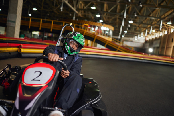 go cart ταχύτητα drive, αφροαμερικανός οδηγός στο κράνος στο κύκλωμα, karting έννοια μηχανοκίνητο αθλητισμό - Φωτογραφία, εικόνα