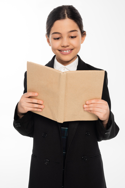 colegiala feliz en uniforme libro de lectura, estudiante con pelo morena aislado en blanco, chica inteligente - Foto, Imagen