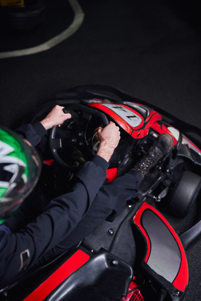 Draufsicht auf den Mann mit Helm und Sportbekleidung beim Go-Kart-Fahren auf Indoor-Rundkurs, Adrenalin-Konzept - Foto, Bild