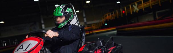 pilota concentrato in casco e abbigliamento sportivo guida go kart su circuito indoor, concetto adrenalina, banner - Foto, immagini