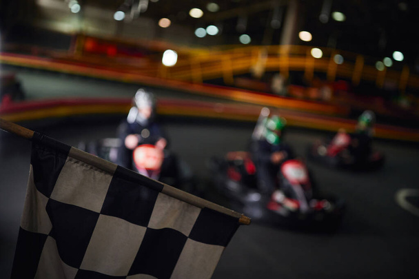 checkered black and white racing flag with drivers on blurred backdrop, go kart concept - Photo, Image