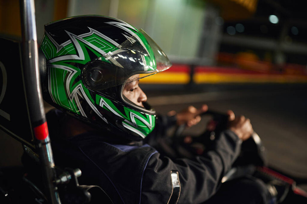 afro-americano go cart racer em capacete dirigindo em circuito interno, corrida de velocidade e automobilismo - Foto, Imagem