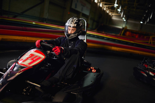 keskittynyt nopeus kilpailija kypärä ajo go kart auto sisätiloissa piiri, moottoriurheilun kilpailun käsite - Valokuva, kuva