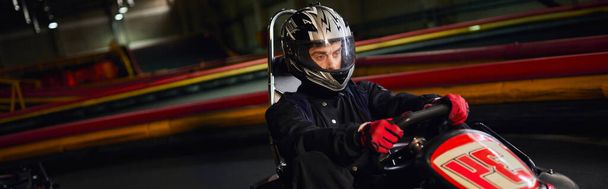 ヘルメット運転の焦点を当てたスピードレーサーは,屋内サーキット,モータースポーツ競技,バナーでカートカーを行います - 写真・画像